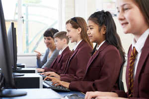 Students and a teacher in an IT room using desktop computers