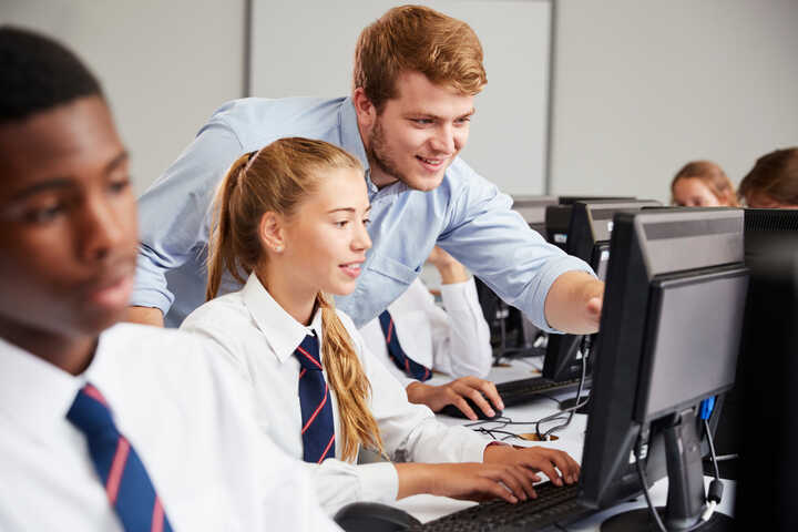 teacher and student working on a desktop computer