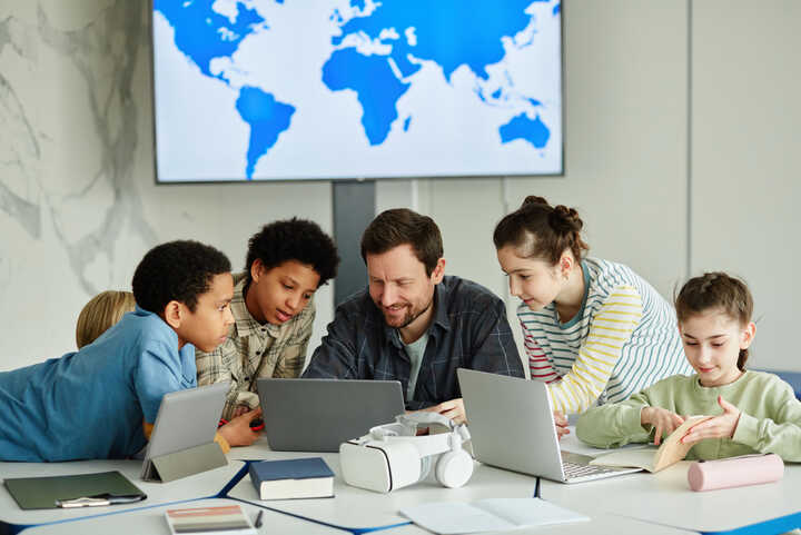 Teacher with students working on laptops and tablets