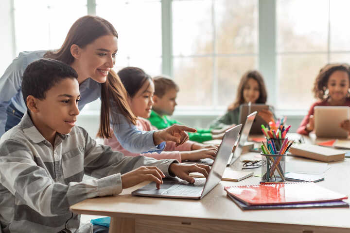 teachers working with students on laptops